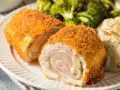 Schab po szwajcarsku, chrupiący panierowany kotlet z serem i szynką, podany z puree ziemniaczanym i brokułami.