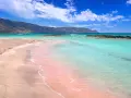 Różowa plaża Elafonisi na Krecie, idealna na wycieczki fakultatywne po polsku. Turkusowa woda, góry w tle.