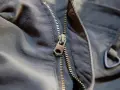 Detalle de una cremallera de chaqueta que se ha salido, mostrando el cursor metálico y los dientes.