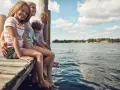 Rodzina siedzi na pomoście nad jeziorem Wilkowskim, ciesząc się słonecznym dniem.