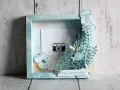 Un cadre photo en bois décoré sur le thème marin avec une méduse, des poissons, des fleurs et une petite caméra.