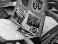 Odkryj, jak zrobić fotoksiążkę, przeglądając stare zdjęcia w albumie. Ręka trzyma kartę z portretami i krajobrazami.
