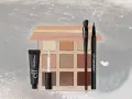 Make-up Produkte: Lidschattenpalette, Primer, Pinsel und Eyeliner auf glitzerndem Hintergrund.