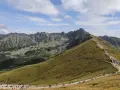 Szlak na Kasprowy Wierch jest popularny, turyści wędrują kamienistą ścieżką pośród zielonych zboczy Tatr.