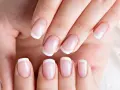 Dłonie z idealnym french manicure, gdzie białe końcówki paznokci lśnią jak tytanowe paznokcie.