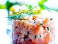 Tartare di salmone fresco, finemente tagliato e condito, guarnito con aneto. Un piatto leggero e saporito.