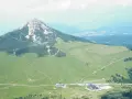 Panoramica delle malghe al Passo Lavazè, con un imponente monte sullo sfondo e sentieri che si snodano tra prati verdi.
