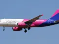 Samolot Wizz Air z różowo-fioletowym ogonem leci na tle błękitnego nieba. Sprawdź wizz discount club cena i leć taniej!