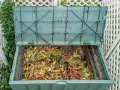 Compostiera verde piena di scarti organici, un esempio di bokashi fai da te per un giardino sostenibile.