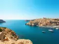 Malta w październiku: błękitne morze, skaliste wybrzeże i zabytkowe miasto z portem pełnym łodzi. Idealna pogoda na zwiedzanie.