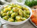 Salade de pommes de terre fraîchement préparée, garnie d'aneth et de ciboule, prête à être servie avec une sauce légère.