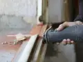 Main d'un artisan utilisant une scie sauteuse pour la dépose totale d'une fenêtre. Estimation du prix pose fenêtre dépose totale.
