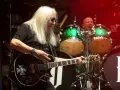 Uriah Heep członkowie na scenie. Mick Box gra na gitarze, a za nim perkusista.