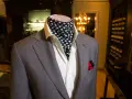 Elegancki męski strój: szara marynarka, biała koszula i fular w grochy. Fular co to? To stylowy dodatek.