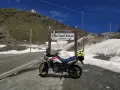 Moto pronta per affrontare il Passo dello Stelvio, con neve ai lati della strada e un edificio in cima alla montagna.