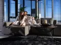 Pareja disfrutando de un momento íntimo en un sofá moderno, ideal para alquileres de temporada con vistas panorámicas.