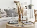 Tavolino rotondo in legno con elementi decorativi che evocano un'atmosfera boho chic: vasi, candele, libri e una scultura di testa.