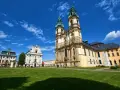 Barokowy kościół i klasztor na tle błękitnego nieba z chmurami. Piękne sanktuaria maryjne w Polsce zachwycają architekturą.