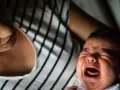 Ein schreiendes Baby, das von seiner Mutter getröstet wird. Vielleicht ein Zeichen für eine frühe Hochbegabung, die sich in intensiven Emotionen äußert.