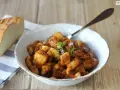 Un plato de sepia con patatas en salsa, decorado con hierbas frescas. Acompañado de pan rústico.