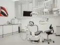Nowoczesny gabinet stomatologiczny z fotelem, unitem i obrazem uśmiechu.