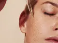 Kropla serum z pipety spada na piegowatą skórę. Czy to retinol? Co to jest retinol i jak działa?