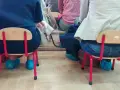 Dostateczny, jaka to ocena? Dzieci siedzą na małych krzesełkach w niebieskich ochraniaczach na buty.