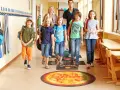 Dzieci i dorośli idą szkolnym korytarzem, stąpając po planszy z planetami. Fajne inicjatywy w szkole promują naukę przez zabawę.