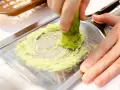 Świeże wasabi jest tarte na metalowej tarce, tworząc zieloną pastę. To właśnie tak powstaje prawdziwe wasabi.