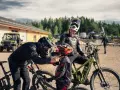 Två cyklister förbereder sig för mtb downhill. En vuxen hjälper ett barn med hjälmen.
