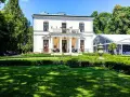 Elegancki pałac Rozalin z kolumnowym portykiem i balkonem, otoczony zielonym ogrodem i nowoczesnym namiotem bankietowym.