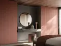 Un moderno angolo trucco in camera da letto con specchio rotondo, sgabello e armadi color pesca.