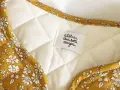 Détail d'une veste matelassée femme avec un tissu fleuri jaune moutarde. Un patron gratuit pour créer ce modèle est disponible.