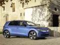 Niebieski samochód elektryczny VW ID. Polo stoi na brukowanej drodze przed kamiennym budynkiem.