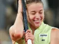 Szczęśliwa Iga Świątek, zwyciężczyni Roland Garros, z rakietą opartą o głowę, w geście triumfu.