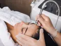 Aesthetician performs microdermabrasion on a woman's forehead. The question of microdermabrasion how often depends on skin type and goals.