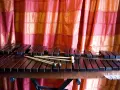 Ksylofon, instrument muzyczny na literę K, z pałeczkami, na tle czerwonej zasłony.