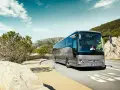 Srebrny Mercedes Tourismo jedzie malowniczą trasą nad morzem.