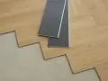 Szary podkład pod panele laminowane, gotowy do ułożenia na betonowej podłodze.