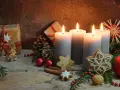 Vier brennende Kerzen im **Hintergrund Adventszeit**, umgeben von Tannenzweigen, Geschenken, Nüssen und Weihnachtsplätzchen.