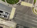 Vista aerea di un incrocio con strisce pedonali bianche e gialle. Auto in attesa nella corsia di preselezione, tram sui binari sottostanti.