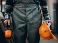 Pracownik w odzieży roboczej trzyma kask i nauszniki. Przepisy dotyczące prania odzieży roboczej są ważne dla bezpieczeństwa.