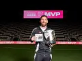 Lionel Messi sonríe en un estadio, sosteniendo un trofeo MLS MVP y un libro. El letrero del estadio dice "LIONEL MESSI MVP".