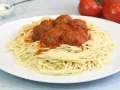 Un plato de espaguetis con albóndigas cubiertos de salsa roja.