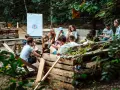 Kinder lernen im Freien beim englisch camp. Eine Tafel mit der britischen Flagge steht im Hintergrund.