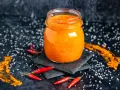 Glas mit leuchtend orangefarbener Sambal Oelek Paste, umgeben von frischen Chilis und grobem Salz. Ein einfaches Sambal Oelek Rezept zum Nachmachen.