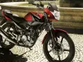 Czerwony motocykl Yamaha YBR 125 na brukowanej ulicy. Sprawdź yamaha ybr 125 dane techniczne, by poznać jego możliwości.