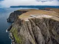 Majestatyczne klify na Nord Kapp, z widokiem na ocean i budynkami turystycznymi.