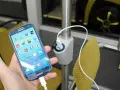 Dłoń trzyma smartfon podłączony do ładowarki USB zamontowanej na słupku w autokarze.