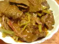 Hígado guisado con cebolla y pimientos verdes en salsa marrón.